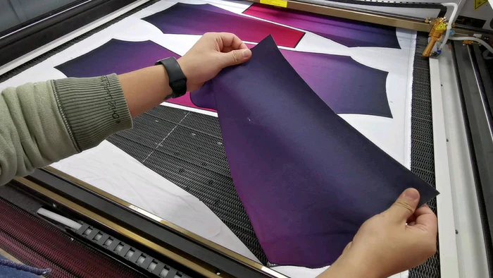 Hands holding fabric sample with cut detail